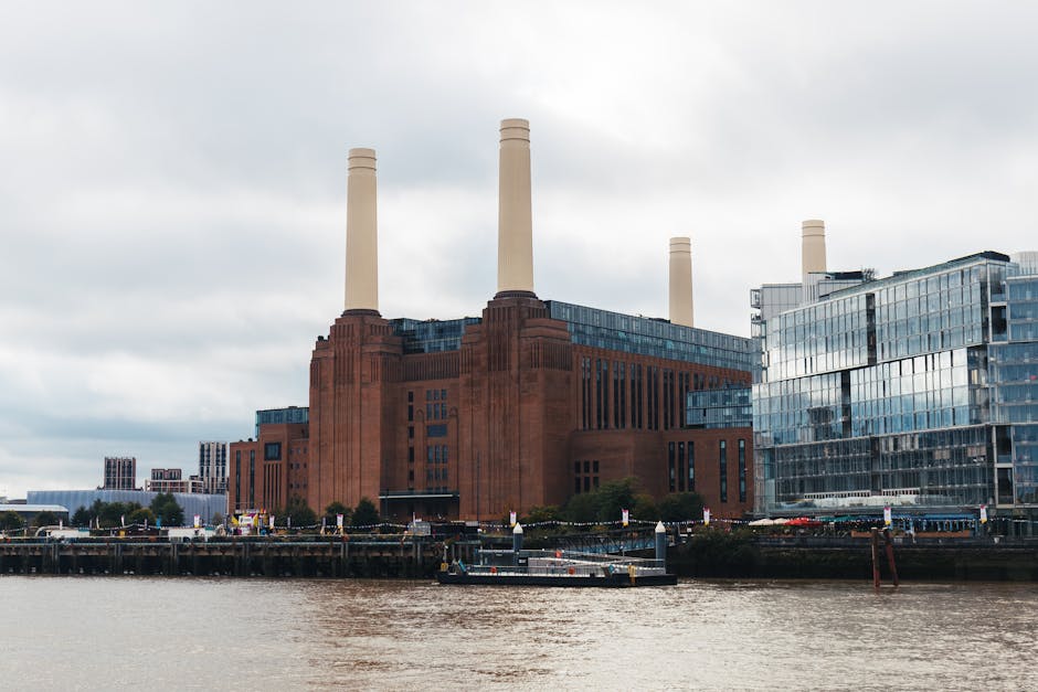 A large industrial building resembling a power station with multiple tall, cylindrical yellow chimneys rising from its concrete and metal facade. The structure is partially covered with white protecti